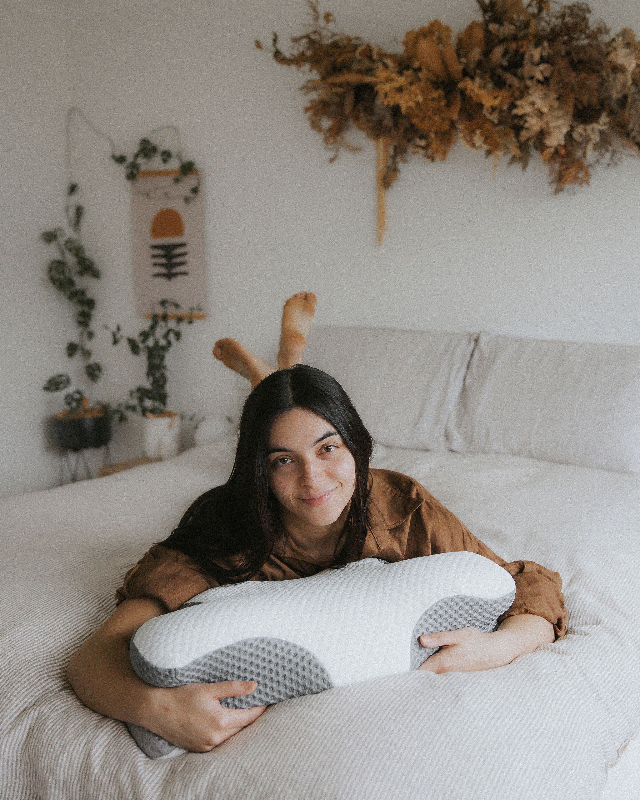 Woman lying on a bed holding a pillow with decorative elements in the background
