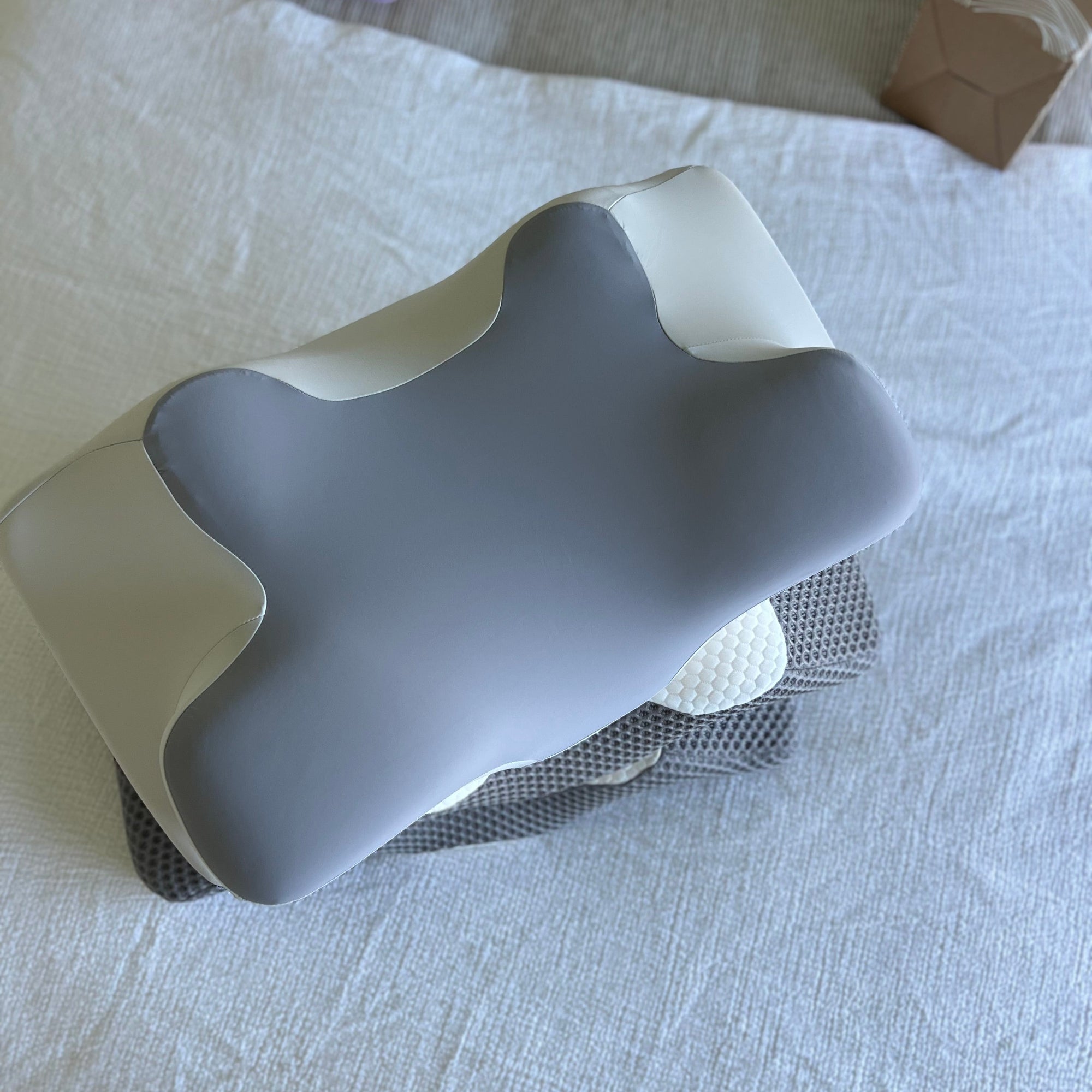 A top-down view of the Dream Sleep ergonomic contour pillow, highlighting its shape for neck support and temperature-neutral fabric.