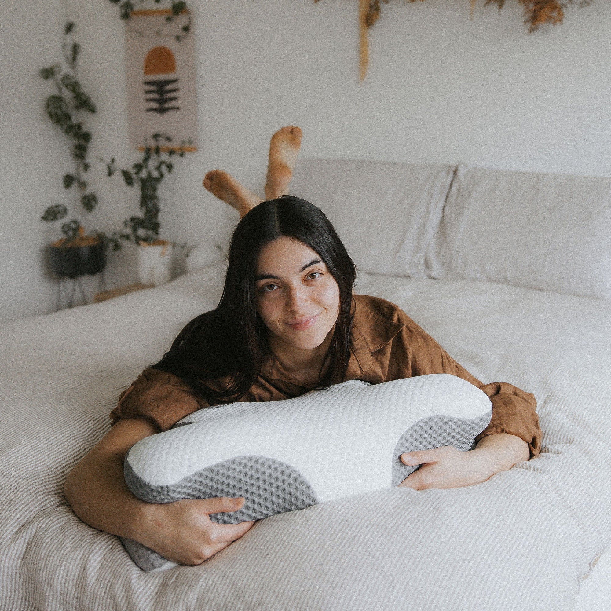 Close-up of the Dream Sleep posture pillow being held by a woman in a bedroom
