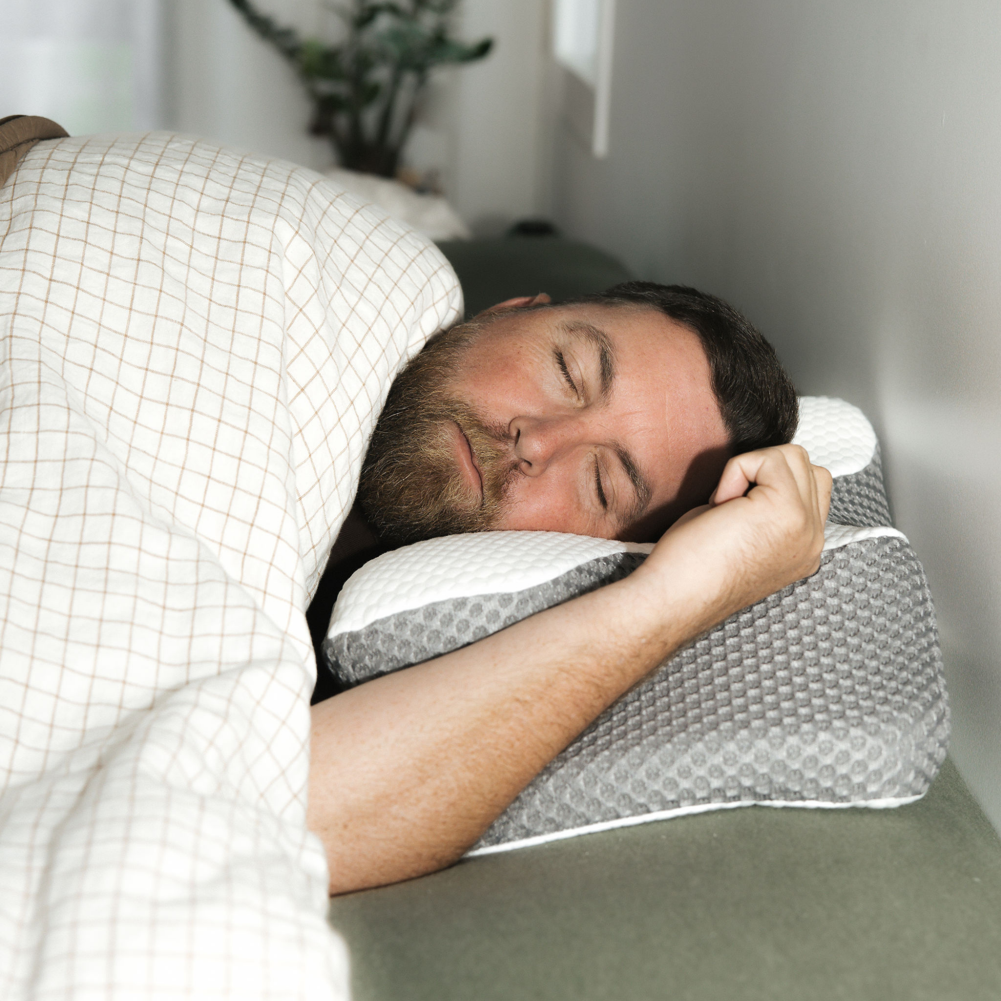 A man sleeping peacefully on a Dream Sleep Posture Pillow, showcasing how the pillowcase perfectly contours to the pillow's ergonomic shape.