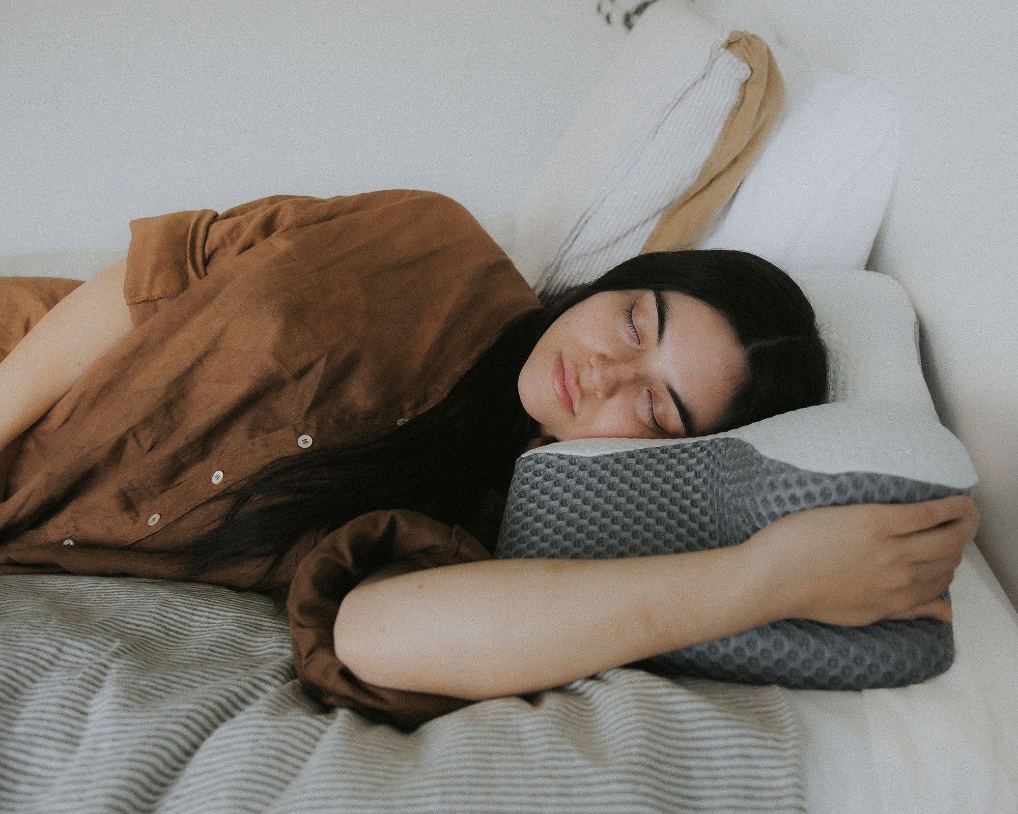 Person resting on a supportive memory foam pillow, highlighting its design for side sleepers and neck pain relief.