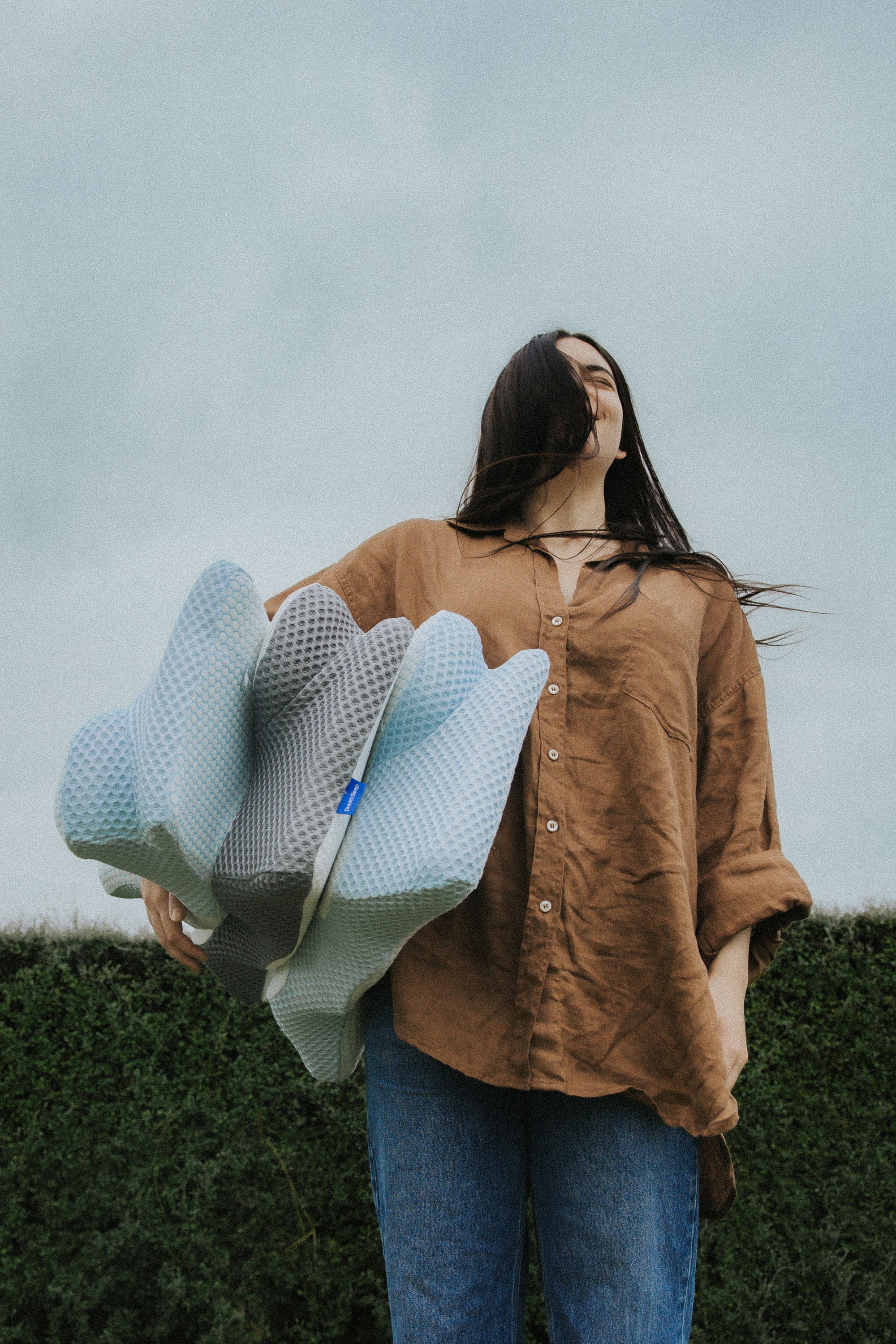 Woman holding the Blue and Grey Posture Pillows, illustrating the size and color options for orthopaedic support and pain relief.