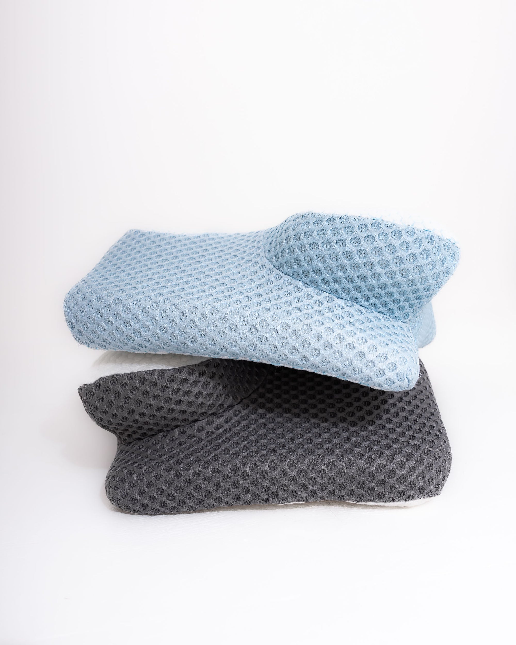 Stacked set of ergonomic contour memory foam pillows in Alpine Blue and Cloud Grey, showing the breathable textured fabric designed for cooling comfort and neck support.